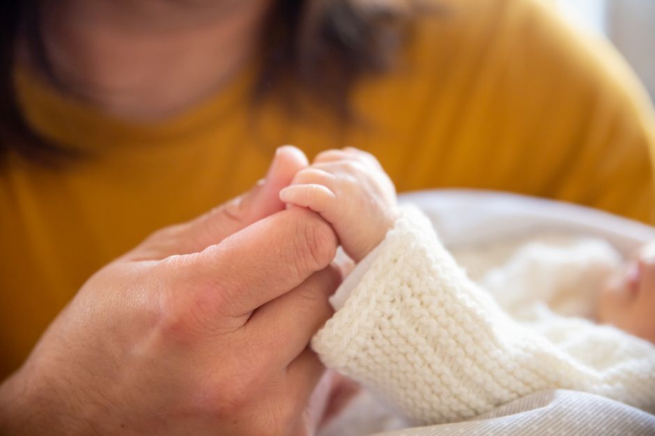 A tender moment capturing a father gently holding his newborn's hand, symbolizing love and care.