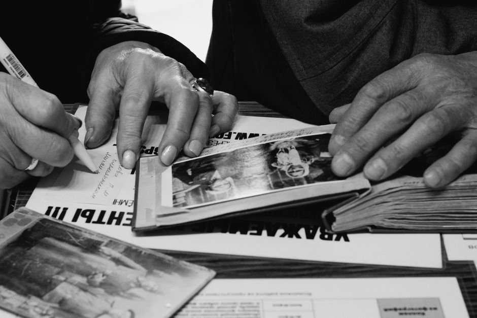 Hands of elderly people examining and writing in photo albums, capturing memories.