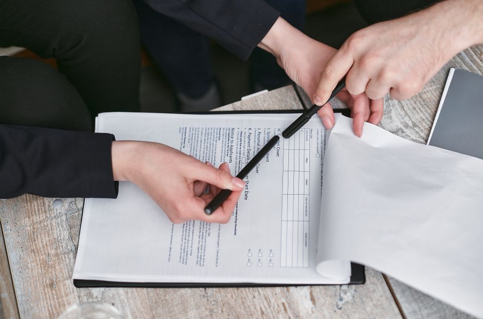Close-up of business hands finalizing agreement with pen on documents.