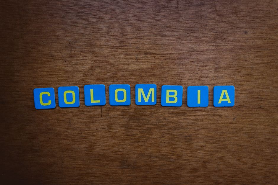 A close-up of colorful tile letters spelling 'Colombia' on a wooden surface.
